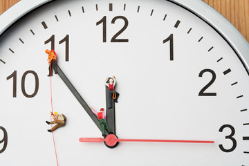 Miniature people climbing a clock