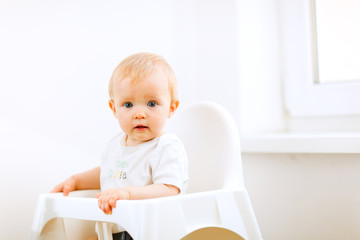 Fototapeta premium Lovely baby sitting in baby chair