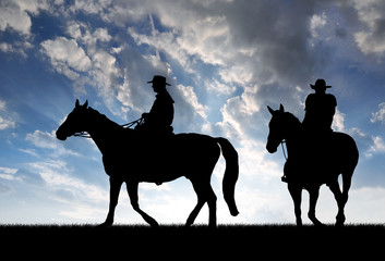 Naklejka premium Silhouette cowboys with horses in the sunset