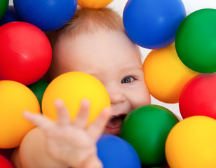 Fototapeta na wymiar Portrait of a smiling infant lying among colorful balls