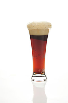dark beer with the foam in a tall glass isolated on white