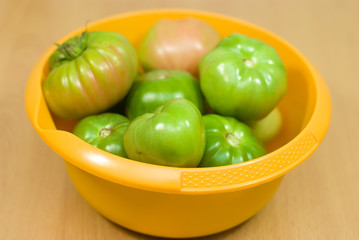 green organic tomatoes in the yellow bowl
