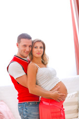 Fototapeta premium Portrait of pregnant woman with husband hugging her tummy