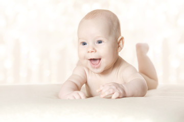 Happy active baby lying on stomach over blanket