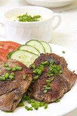 Grilled steak with fresh vegetables un white plate and sauce