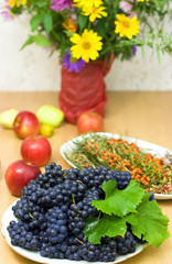 Fototapeta na wymiar fresh black grape on a background of fruits and flowers