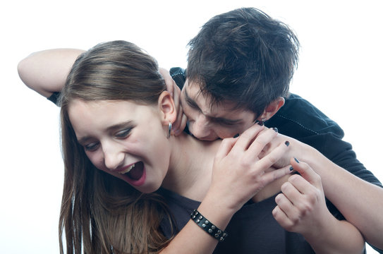 Vampire teenage boy biting neck of the frightened teenage girl