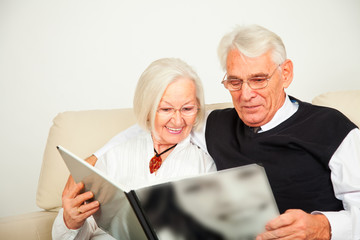Senioren Paar sitzt auf dem Sofa und schauen ein Buch an