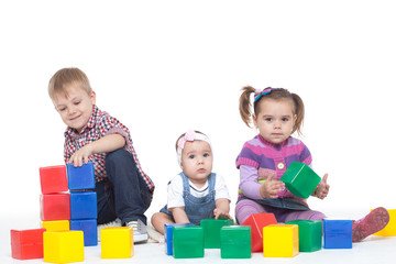 boy and two little girls play bright cubes