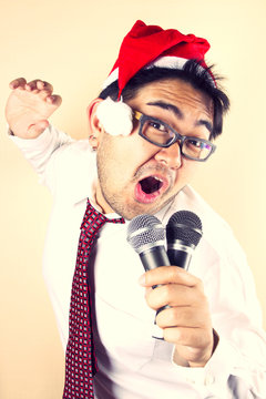 businessman wear Santa hat singing with two microphone.