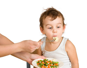 Little boy tasting vegetable salad. Isolated on white