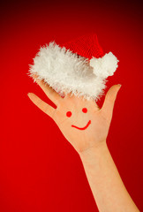 Human's palm with smile on it wearing Santa's hat
