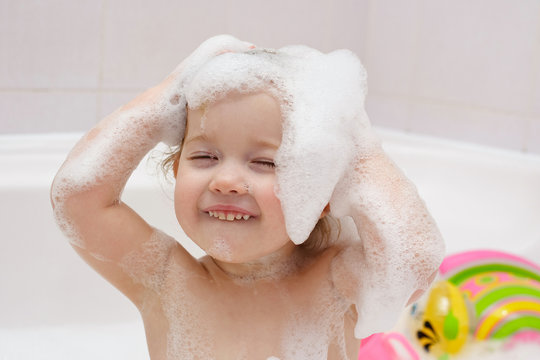 little child is washing her hair in bath