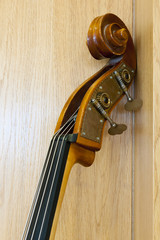 the top of a cello neck leans on a wooden wall © A2LE