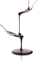 Chocolate poured into a spoon and from it to another spoon