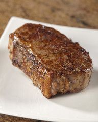 Fan fried steak on a square white plate.