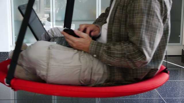Male - Working with Notebook and Mobile in Swinging Seat