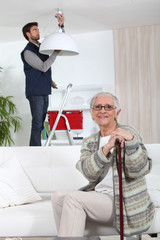 young man fixing lamp for older woman