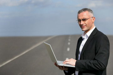 Man with laptop stood on road