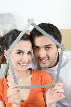 Couple holding house-shaped measuring device