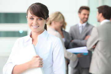 Smiling young woman with colleagues in the background