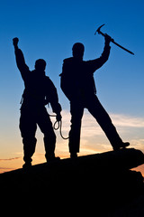 Silhouette of two climbers with hands up