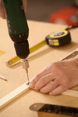 drilling a hole in the wood with an electric drill