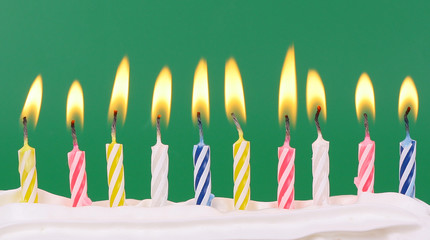 10 lit birthday candles in bright colors with green background