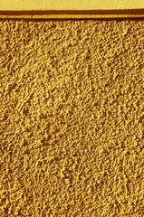 Yellow painted textured wall closeup.
