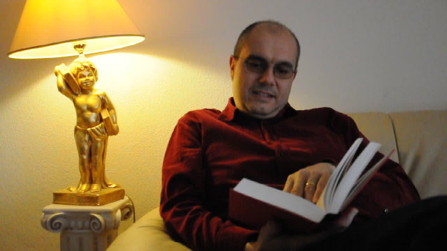 Mann liest ein Buch auf dem Sofa