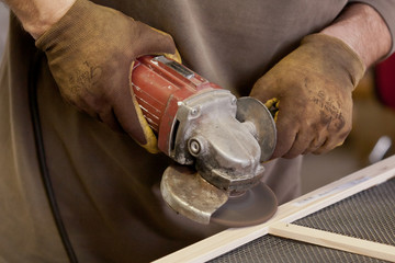 man with dirty gloves handling an angle grinder