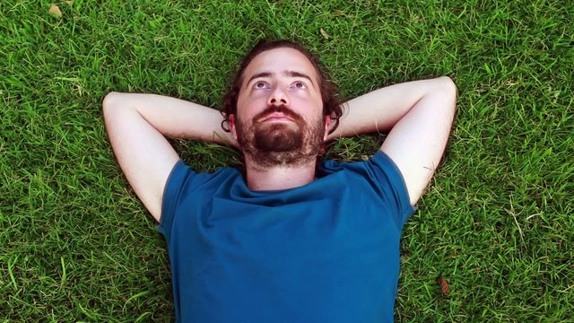 Young guy lie down on grass