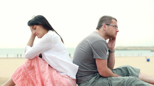 Relationship difficulties, young couple sitting by the beach