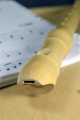 A wooden recorder on sheet music. Selective focus