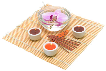 candles, incense sticks and orchid on a white background closeup