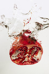 Pomegranate splashing into water - obrazy, fototapety, plakaty