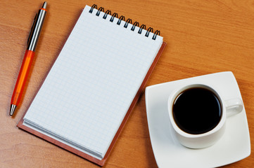Pen, notebook and coffee on table.