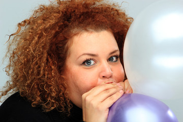 young woman in black shirt inflating balloon