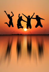silhouette of girls jumping in sunset at beach