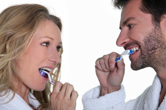 Man And Woman Brushing Teeth