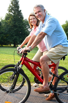 Senior couple cycling in park.