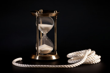 Sand clock and rope on black background