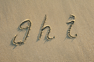 Fototapeta na wymiar litery alfabetu odręcznie w piasku na plaży