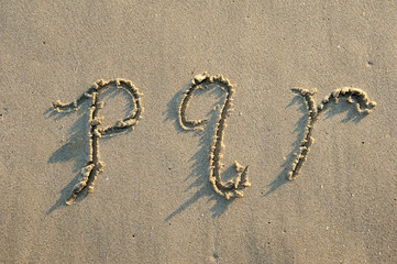 alphabet letters handwritten in sand on beach