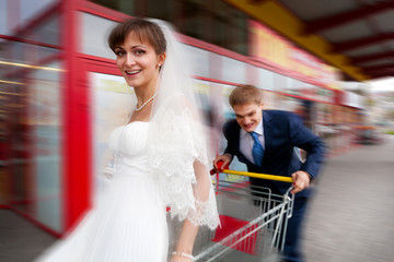 Bride and groom riding on shopping cart