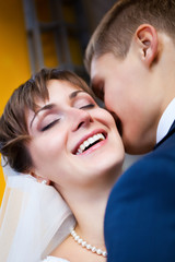 Bride smiling while groom telling her something