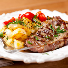 Grilled pork steak with roasted potatoes and herbs