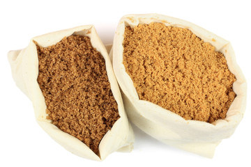 Two types brown sugar in white fabric bags.