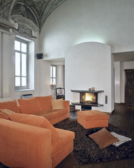 divano arancione davanti al camino acceso in casa moderna