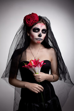 Serious woman in skull face art mask and flowers